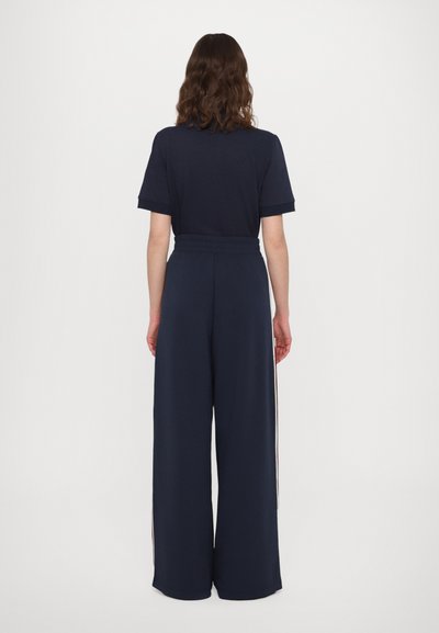 Navy two-piece outfit featuring a short-sleeve top with a relaxed fit and wide-leg pants with side stripes and an elastic waistband.