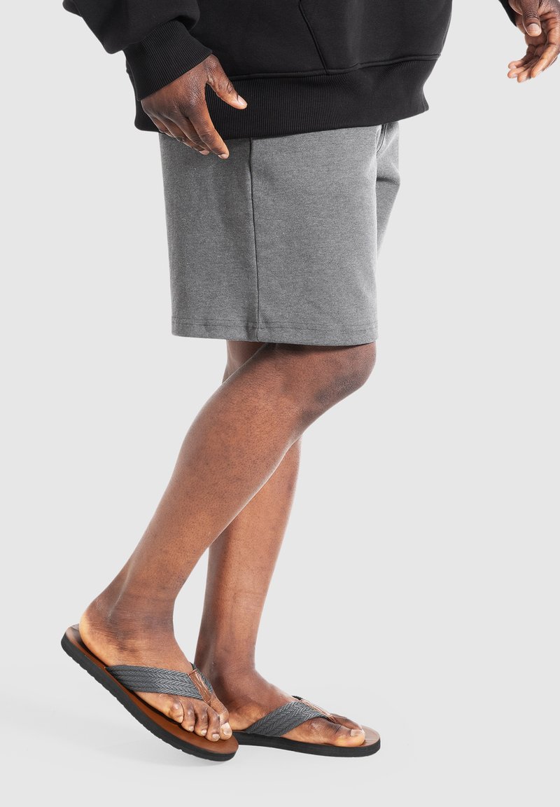 Grå bomulds shorts med en afslappet pasform, parret med sorte og grå klipklapper med en tekstureret rem og brun sål.