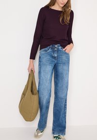 Purppuranvärinen ribbineulottu pitkähiha-pusero, yhdistetty vaaleansinisillä leveälahkeisilla farkuilla. Kädessä vaaleanoliivinvihreä toppalaukku, jalassa vihreänä reunustetut tennarit.