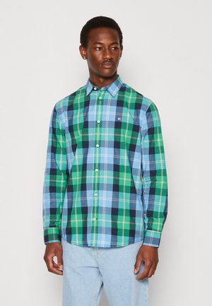 Camisa de cuadros en colores verde, azul y marino, con cuello abotonado, mangas largas y un pequeño logo en el pecho. Tejido de mezcla de algodón.