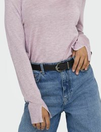 Lichtroze lange mouwen gebreide top met een relaxte pasvorm en geribde manchetten, gecombineerd met hoge blauwe denim jeans en een zwarte riem met een ronde gesp.