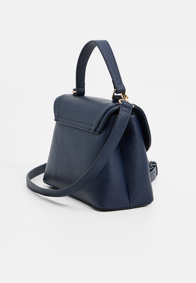 Sac à main en cuir texturé bleu marine avec poignée supérieure et bandoulière détachable, forme trapézoïdale structurée, accents en matériel doré.