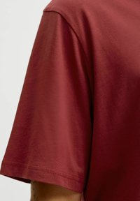 Bordeaux rood T-shirt met korte mouwen, een soepele textuur en een ronde halslijn, voorzien van netjes gestikte zoom- en mouwranden.