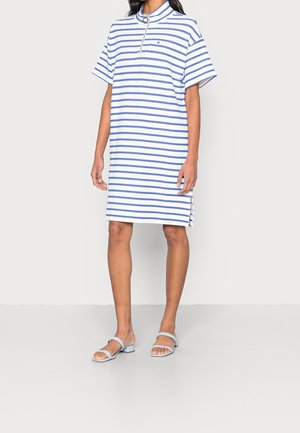 Gestreiftes Kurzarmkleid in Blau und Weiß, mit einem Kragen und einem halben Reißverschluss. Kombiniert mit hellblauen flachen Sandalen.