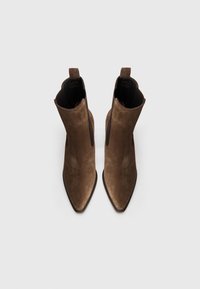 Bottines en suède marron à bout pointu, dotées de panneaux latéraux en élastique et de languettes pour un enfilage facile. Texture lisse et design effilé.