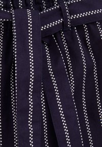 Tums navy zila auduma svārki ar baltām punktotām vertikālām svītrām, ar piesietu jostu viduklī un plisējumiem, kas piešķir papildu tekstūru un dizaina detaļas.