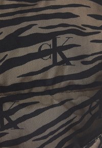 Czarna siateczkowa tkanina z wzorem w paski zebry, z fakturowaną powierzchnią i subtelnym beżowym tłem. Zawiera ciemne akcenty i branding.