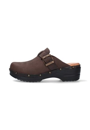 Zoccolo marrone slip-on con cinturino regolabile con fibbia, dettagli con rivetti sulla suola nera e un leggero tacco per maggiore altezza e supporto.
