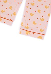 Roze katoenen stof met een algeheel patroon van gele croissants en kleine rode hartjes, met een rode accent aan de zoom.