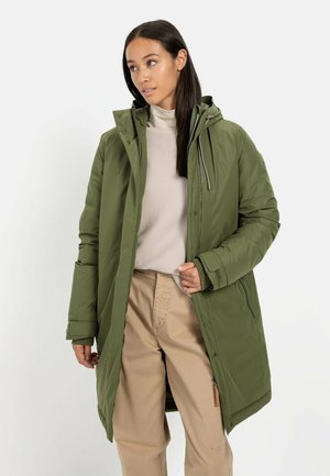 Groene gevoerde parka jas met een capuchon, voorzien van een ritssluiting, zijzakken en een zachte textuur. Draagt over een lichtbeige trui en broek.