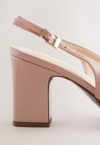 Lachsrosa Lackleder-Slingback-Sandale mit klobigem Absatz und goldfarbenem Schnallenverschluss. Glatte Textur und offene Seiten für Atmungsaktivität.