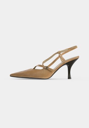 Chaussure à talon haut slingback beige pour femme, bout pointu, talon fin noir et petite boucle sur la bride latérale.