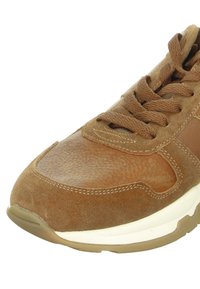 Brown sneaker with a combination of smooth leather and textured suede, round toe, and prominent lacing. Features a white midsole and rubber outsole.