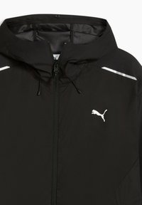 Veste coupe-vent noire avec capuche, fermeture éclair à l'avant et accents réfléchissants. Logo Puma blanc distinctif sur la poitrine. Texture lisse.
