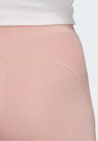 Ljusrosa leggings gjorda av elastiskt tyg, med en slät yta, elastisk midja och rena sömmar längs sömmarna.