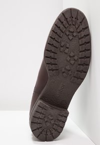 Pohja tummanruskeasta nahkakengästä syvällä kuvioinnilla, brändin nimi "Gabor", koko 4½, ja "Valmistettu Portugalissa" -leima näkyvissä.