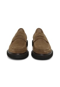 Paar pruune seemisnahast mokasiine, mustade kummist talladega, ühendatud detailidega ja klassikalise münditasku disainiga.