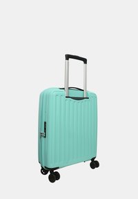 Valigia rigida verde menta con texture a righe, manico argentato retrattile, zip laterale e quattro ruote piroettanti nere per la mobilità.