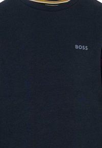 Granatowa bawełniana koszulka z krótkim rękawem, z teksturowanym ribbed, okrągłym dekoltem oraz małym szarym logo "BOSS" na lewym piersi.