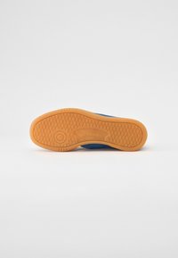 Blå sneakers med ovandel i ett texturerat tyg och en sula i gummigummi. Har diamantmönster för grepp och "Reebok"-märke på sulan.