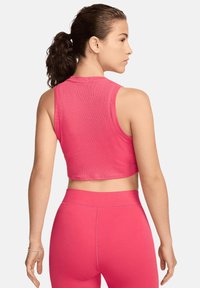 Top cropped rosa con texture a coste, design senza maniche e scollatura rotonda, abbinato a leggings a vita alta coordinati.