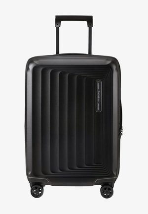 Schwarzer Koffer mit geriffeltem Design, aus hartem Kunststoff hergestellt. Verfügt über einen teleskopischen Griff und vier Rollen für Mobilität. Mit Reißverschluss.