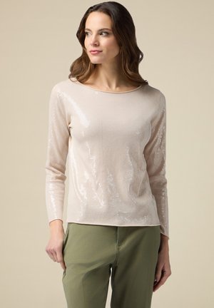 Hellbeige Langarmpullover mit strukturiertem Muster und Pailletten auf der Vorderseite, kombiniert mit olivgrünen Hosen. Weicher Stoff und lässige Passform.