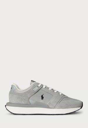 Baskets basses grises avec lacets blancs, logo noir sur le côté, panneau en mesh texturé et semelle blanche avec semelle extérieure noire.