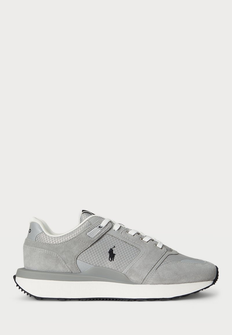 Baskets basses grises avec lacets blancs, logo noir sur le côté, panneau en mesh texturé et semelle blanche avec semelle extérieure noire.