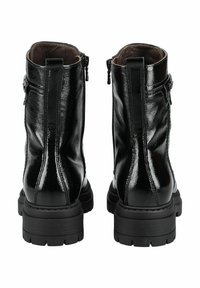 Bottes de cheville en cuir verni noir avec une semelle épaisse, des zips visibles et une finition lisse, dotées de coutures verticales pour le détail.