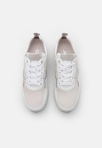 White sneaker with perforated beige and grey textile panels, lace-up design, scalloped accents, and logos on the insoles.