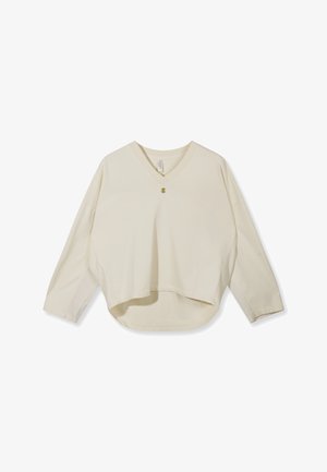 Haut ample beige à manches longues avec col en V, un bouton sur la poitrine, et un ourlet légèrement plus long à l'arrière.