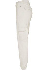 Beige cargobukser med slim fit, elastiske manchetter, sidelommer til cargo og knaplukning. Fremstillet af holdbart stof med en glat tekstur.
