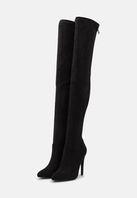Botas negras de ante por encima de la rodilla, con punta afilada, tacón de aguja y parte superior sin costuras con un sutil detalle de costura.