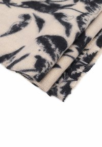 Tessuto misto lana in crema con motivo floreale nero, caratterizzato da una consistenza morbida e bordi sfilacciati visibili, piegato ordinatamente per l'esposizione.