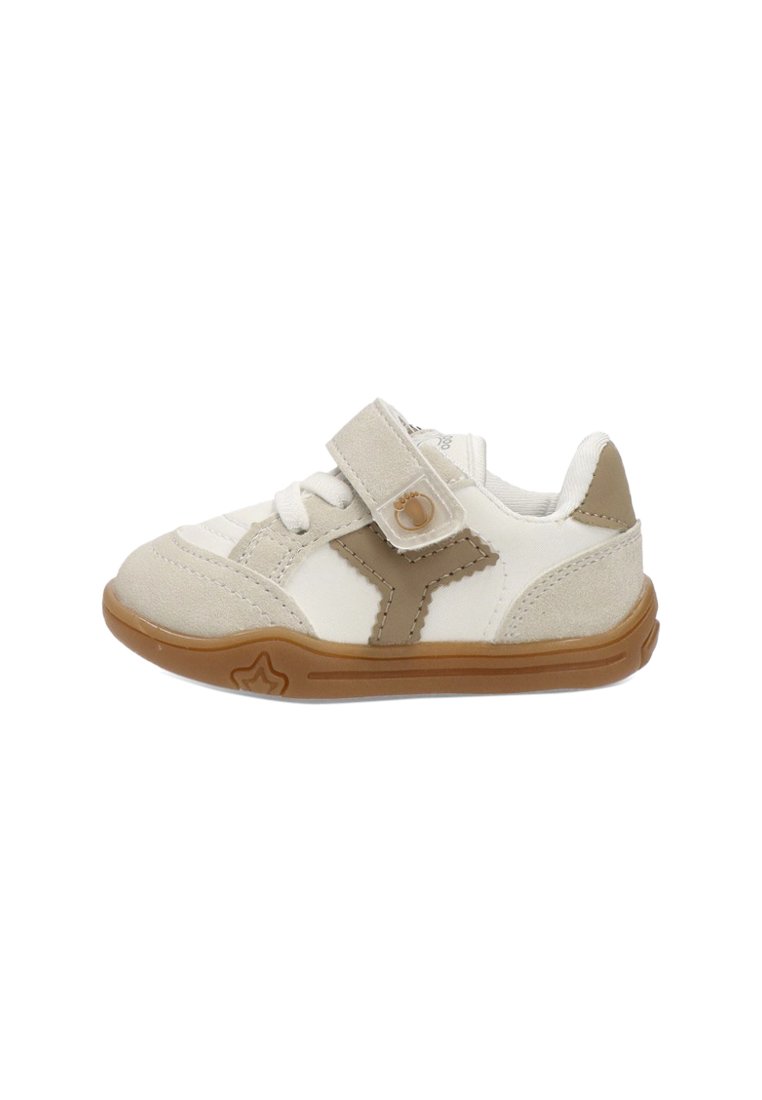 Zapatilla para niño pequeño en blanco y beige con suela de goma marrón, tira de Velcro, cordones y un diseño de estrella en el lado externo de la suela.