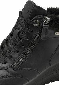 Bottines en cuir noir avec fermeture éclair sur le côté, lacets texturés et doublure en fausse fourrure au col. Semelle en caoutchouc sculptée avec perforations.