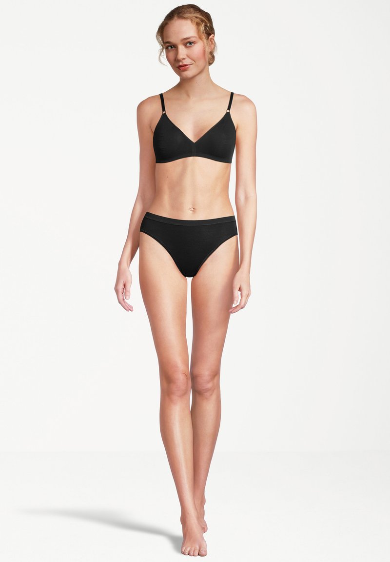 Schwarzer kabelloser BH mit dünnen verstellbaren Trägern und dazu passenden hochgeschnittenen Panties. Glatte Textur und minimalistisches Design.