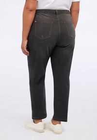 Vaqueros tapered negros con un acabado texturizado y cinturilla elástica, que cuentan con bolsillos traseros y detalles de costura en contraste.