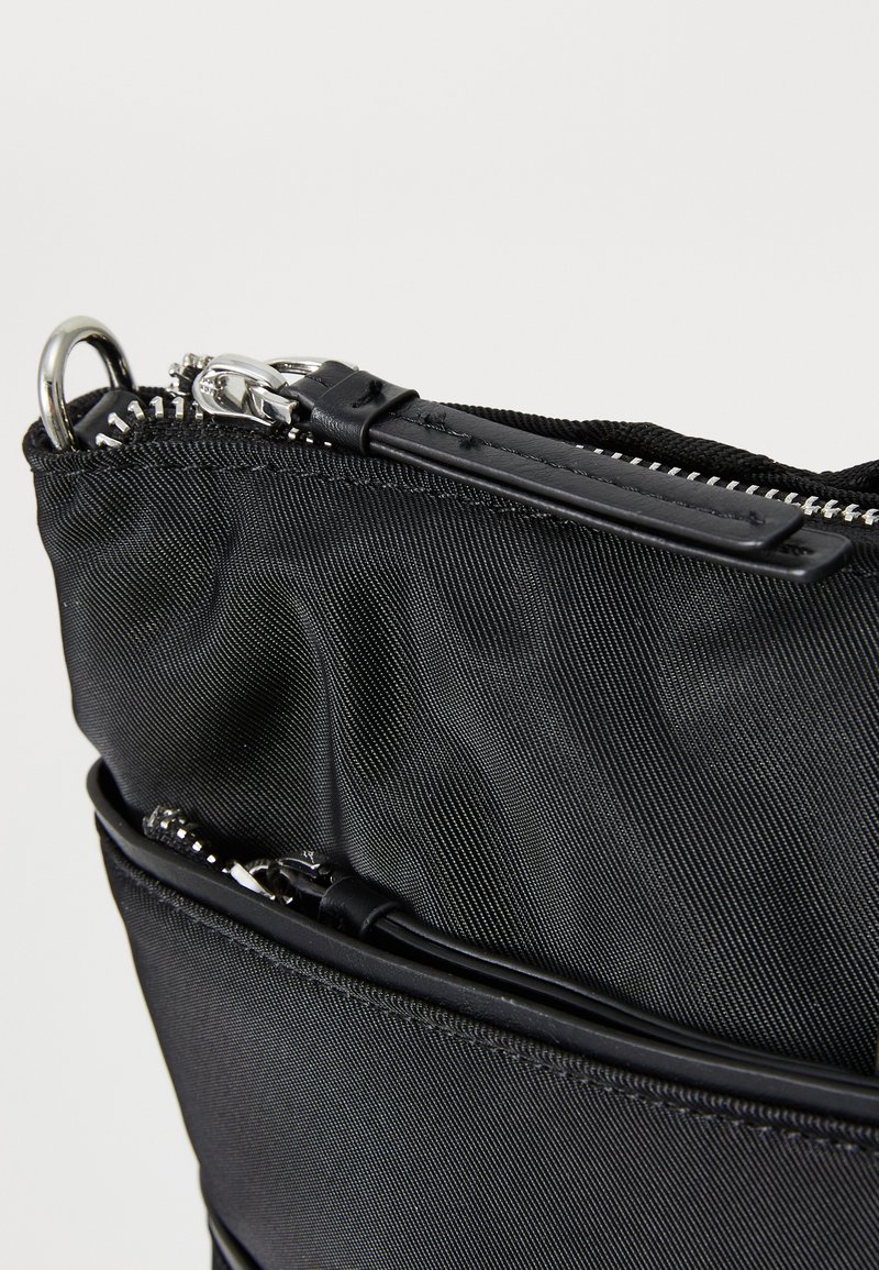 Borsa in nylon nera con chiusura a zip, caratterizzata da una superficie liscia e una cerniera metallica argentata. Include un dettaglio decorativo nella parte superiore.