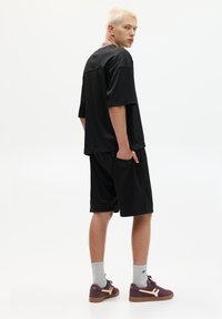 Sort mesh t-shirt og shorts sæt, med løs pasform, lommer, og parret med burgundy sneakers og grå sokker.