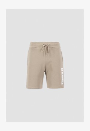 Pantalones cortos en un tono beige claro, hechos de una tela suave, con una cinturilla elástica y cordones, y un detalle de logotipo blanco en la pierna izquierda.