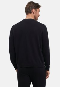 Maglione nero a maglia con collo rotondo, polsini a coste e orlo dritto. Texture liscia, design semplice e materiale di peso medio.