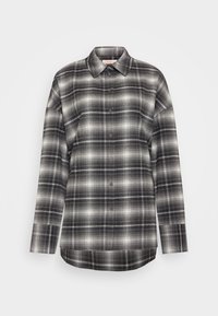 Camicia a maniche lunghe a scacchi in tonalità di nero, grigio e bianco. Caratterizzata da una chiusura a bottoni sul davanti, colletto a punta e una vestibilità rilassata con orlo dritto.