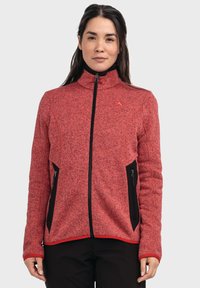 Rote Fleecejacke mit hohem Kragen, Reißverschluss vorne, schwarzen Reißverschlusstaschen und Akzentnähten. Verfügt über ein strukturiertes Strickmuster.