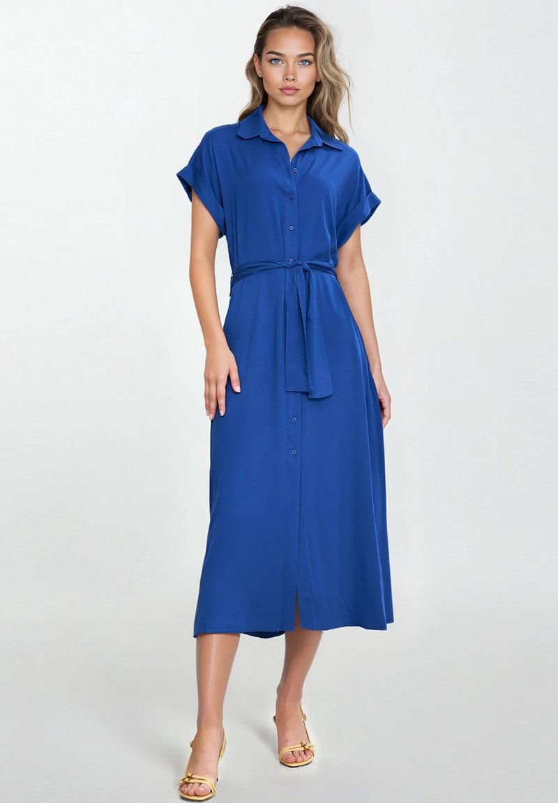 Niebieska sukienka zapinana na guziki, wykonana z lekkiego materiału, z kołnierzykiem, krótkimi podwiniętymi rękawami, paskiem w talii oraz do połowy długości z rozcięciem z przodu.