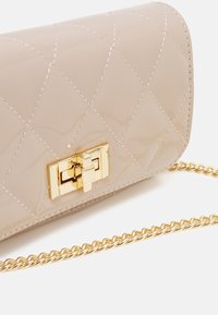 Beige lakovaná kožená kabelka s prošívaným vzorem, zlaté kování s klipem a odnímatelný zlatý řetízkový popruh.