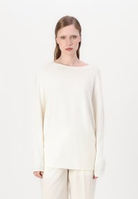 Prevelik, lahkoten pulover v odtenku off-white. Ima širok izrez, rebraste manšete in gladko, teksturirano tkanino.