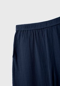 Navyblauwe, gestructureerde stof met een geplooide tailleband; het ontwerp heeft zachte plooien en zijzakken voor een casual, comfortabele pasvorm.