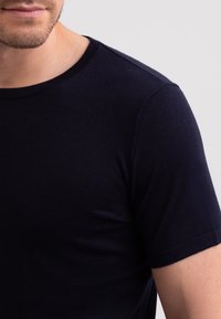 Marinblå bomulls t-shirt med rund hals och korta ärmar, slät textur och subtila söm detaljer på axlarna.